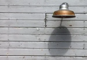An old fashioned lamp mounted to the side of a barn.