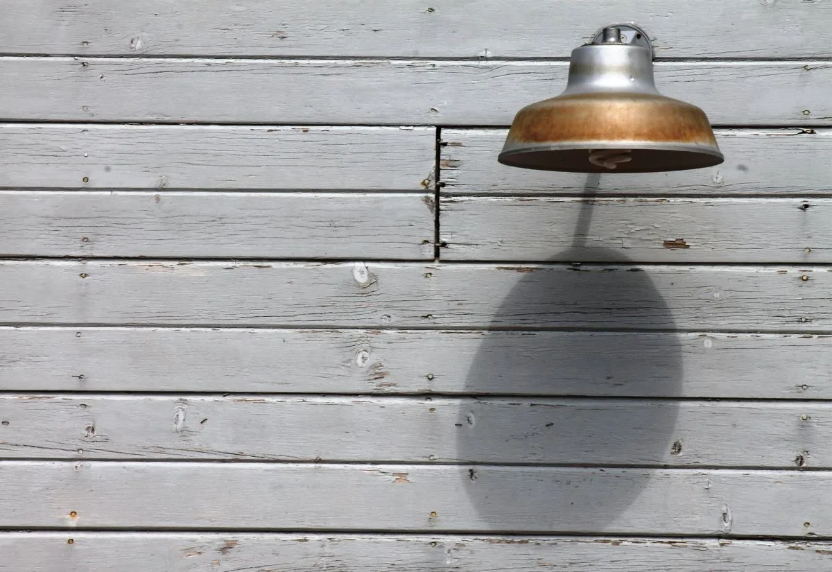 An old fashioned lamp mounted to the side of a barn.