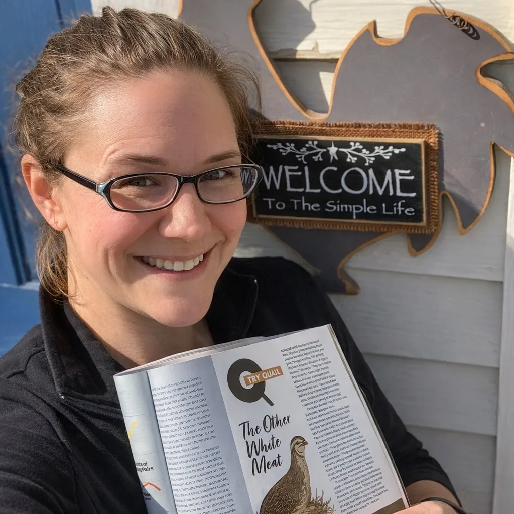 Smiling woman standing outdoors, holding open Downeast Magazine to an article titled “Q is for Quail: The Other White Meat,” from the March 2023 issue.
